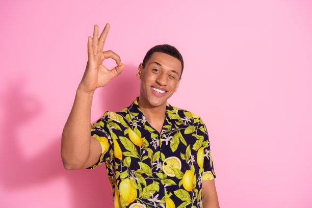 迷人的年轻人的照片肖像眨眼秀ok符号穿着时尚的热带印花衣服孤立在粉红色的背景图片下载