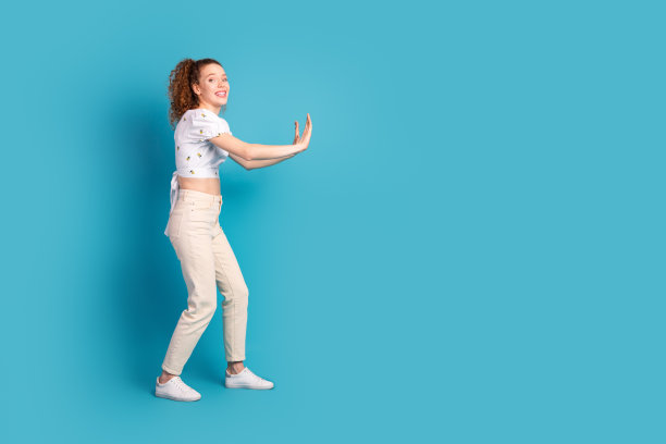 迷人的年轻女子全身照片推墙空的空间穿着时尚的白色衣服孤立在蓝色的背景图片下载