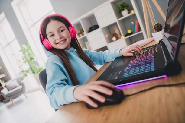 照片正面漂亮可爱的女孩小玩家玩在线视频电脑游戏在室内的房子图片下载