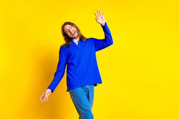 照片中，一个开朗、积极、快乐的男人穿着时髦的蓝色衣服，孤立在黄色的背景上图片下载