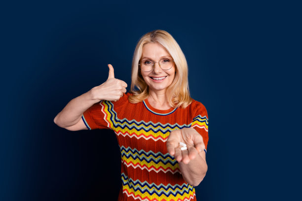 照片可爱的健康的女人穿着时尚的衣服推荐药丸隔离在深蓝色的背景图片下载