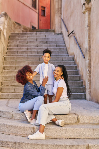 家庭时光的照片，两个女人和一个孩子坐在台阶上。看着镜头图片下载