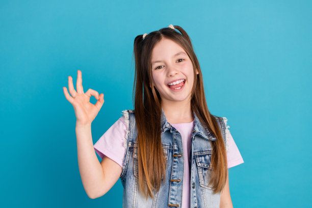 可爱的小女孩的照片肖像显示好兴奋穿着时尚的牛仔衣服孤立的蓝色背景图片下载