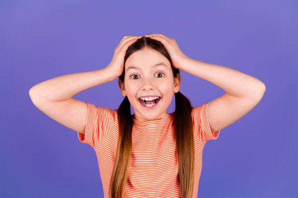 可爱的小女孩的照片肖像触摸头兴奋穿着时尚的红色服装孤立的紫色背景图片下载