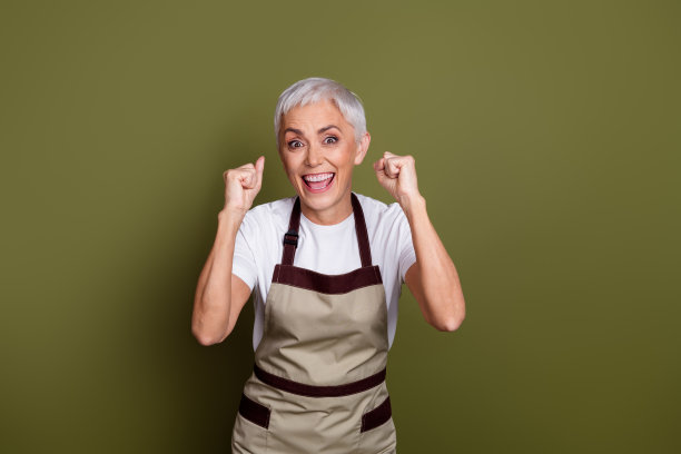 开朗幸运的女士穿着围裙拥有咖啡馆的照片上升的拳头空空间孤立的绿色背景图片下载