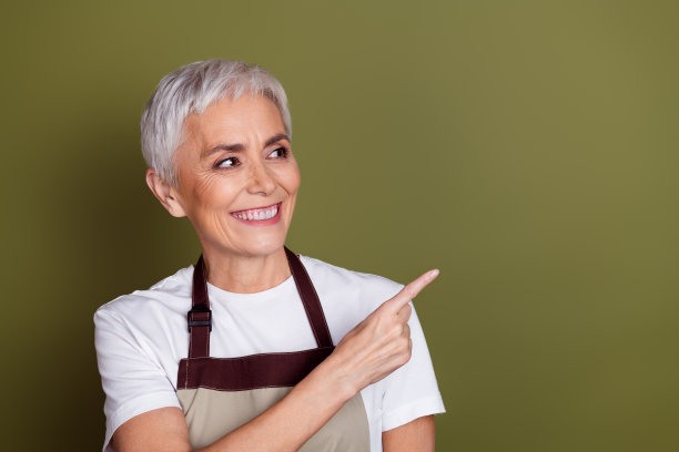照片上光鲜迷人的女士穿着围裙准备饮料，显示看起来空的空间孤立的绿色背景图片下载