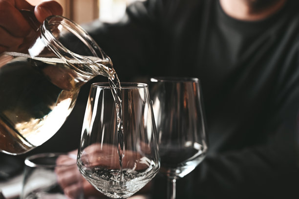 把白酒倒进玻璃杯里。图片下载