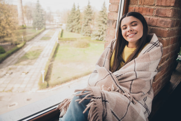 迷人的少女的照片看书享受温暖盖毯子坐在窗台上穿黄色的衣服现代室内平坦的室内图片下载