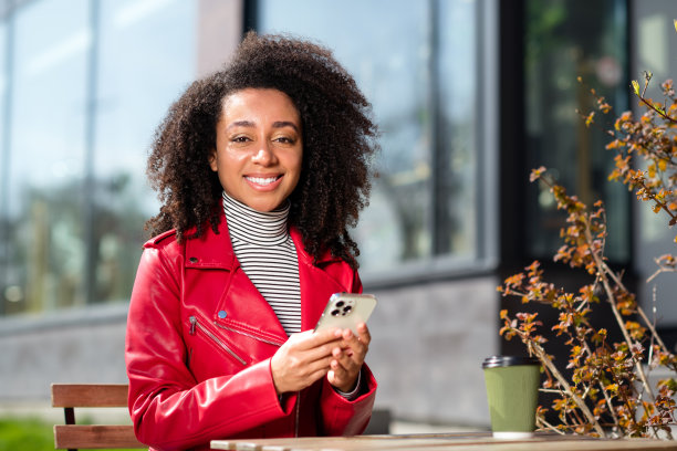 闪亮可爱的女孩穿着皮革红色夹克享受咖啡聊天现代设备走在户外城市街道的照片图片下载
