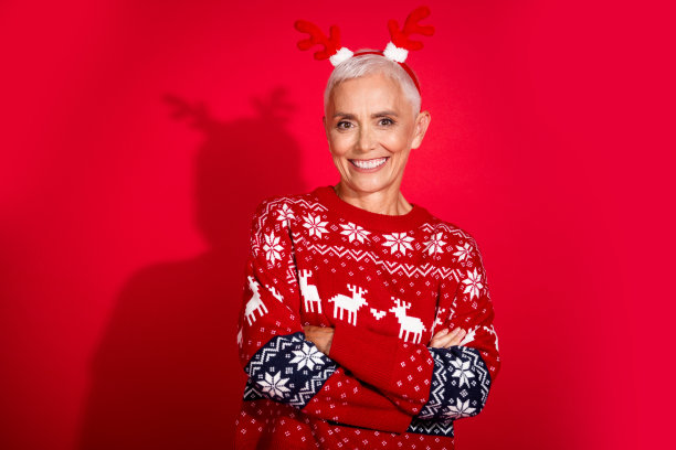 照片肖像漂亮的退休女鹿角交叉双手穿装饰品毛衣庆祝圣诞节孤立的红色背景图片下载