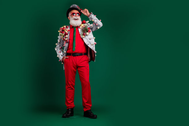 老酷男人的全长照片触摸帽子看空空间穿装饰球小玩意在夹克上太阳镜孤立的绿色背景图片下载