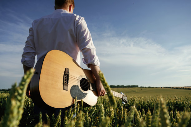 音乐家用的是原声吉他。穿白衬衫的男人在农田里图片下载