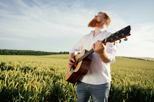 手里拿着吉他。穿白衬衫的男人在农田里图片下载
