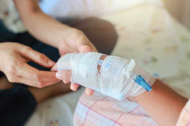 在医院病房里，母亲关切地握着她生病的孩子的手。在医院输液一管生理盐水，因为它是甲型流感，关于治疗的概念，紧急，医学，化疗，生病。图片下载