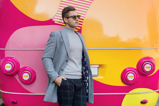 穿着灰色外套的时尚男士，背景是一辆红色公共汽车。图片下载