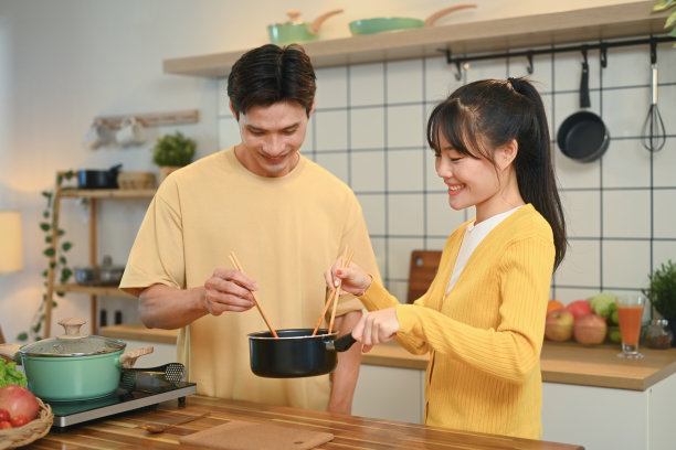 快乐的年轻夫妇一起在厨房的柜台上做饭。人、食、家的厨房理念图片下载