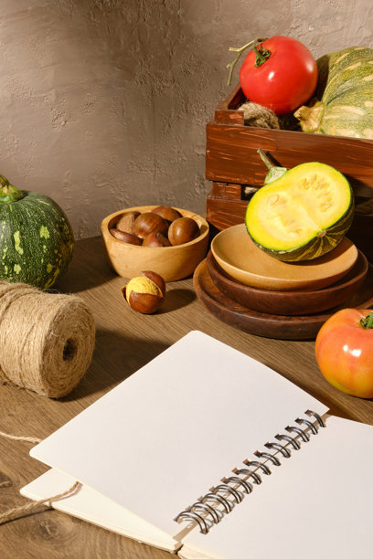高角度拍摄木质台面，展示空白的笔记本和新鲜的秋季蔬菜。烹饪主题照片用于食品广告，空白处用于设计图片下载