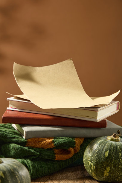 这张照片以秋天为主题，复古风格，一摞书放在绿色的毛衣上，旁边是绿色的南瓜，在棕色的背景上。从正面拍摄的特写，文字的复制空间图片下载