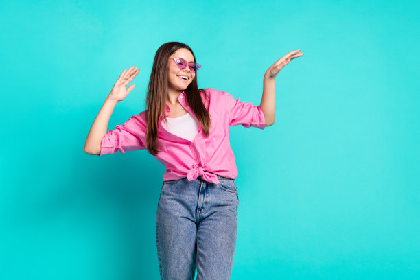 照片肖像迷人的少女太阳镜舞蹈有乐趣好心情穿着时尚的粉红色衣服青色在蓝色的背景图片下载