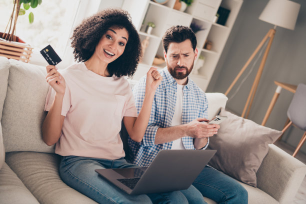 两个漂亮的年轻伙伴的照片借记卡笔记本电脑智能手机空闲时间周末现代公寓室内图片下载