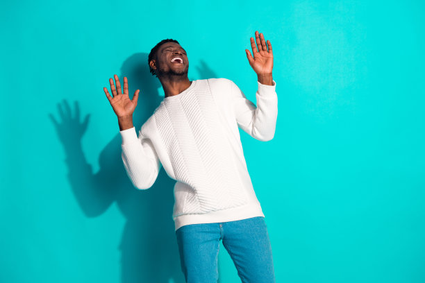 照片上有魅力的年轻人穿着时尚的白色衣服，在青色的背景上笑得很开心图片下载