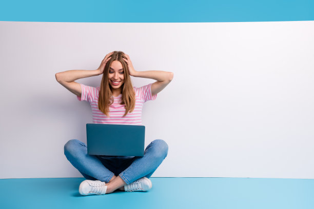 迷人可爱的可爱女人的照片，穿着时髦的粉红色衣服，坐在地板上，用小工具把空间隔离在蓝色的背景上图片下载