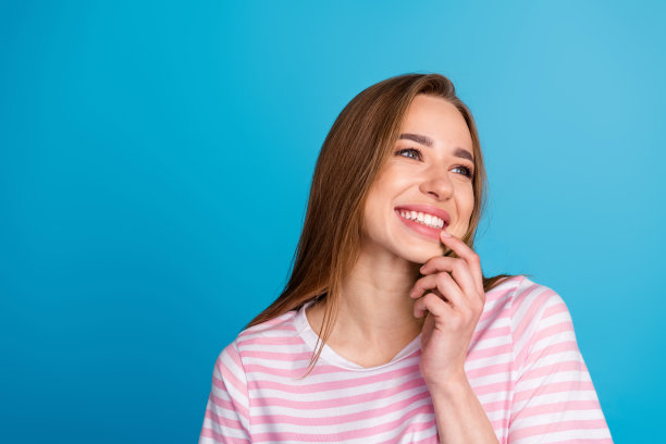照片肖像迷人的年轻女子梦幻般的看空空间穿着时尚的条纹粉红色的衣服孤立在蓝色的背景图片下载