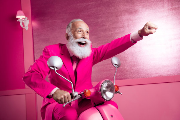 时髦的老商人骑着自行车在家里室内的粉红色墙壁上疾驰的照片图片下载