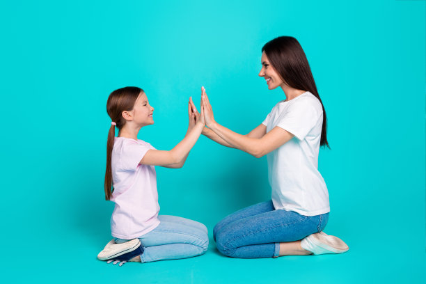 照片开朗可爱的女孩和妈妈有乐趣穿白色时尚的衣服孤立的青色背景图片下载