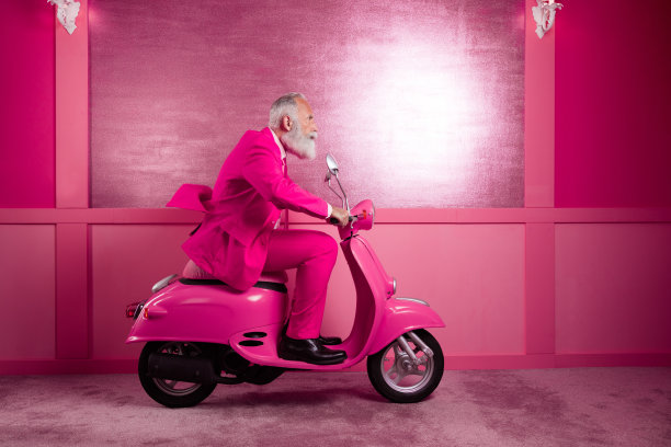 侧面照片成熟的爷爷骑着滑板车快速穿粉红色的运动靴在大厅内图片下载