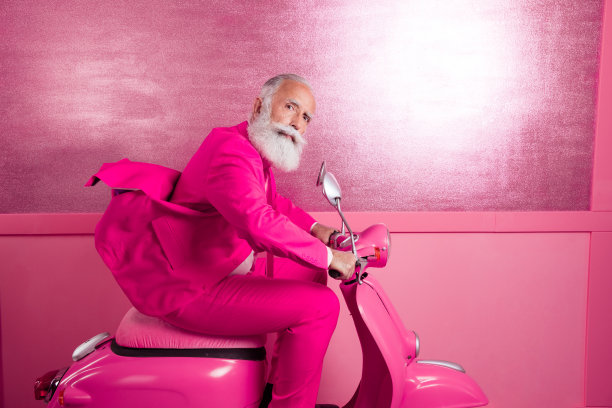 侧面照片自信成熟的爷爷开着高速摩托车，穿着粉红色的运动夹克图片下载