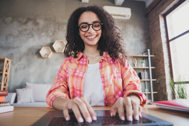 照片积极的好心情的女人穿着橙色衬衫聊天键盘现代小工具在室内的房子公寓房间图片下载