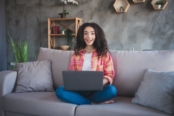 积极的好心情的女人穿着橙色衬衫，微笑着在室内交流现代小工具的照片图片下载