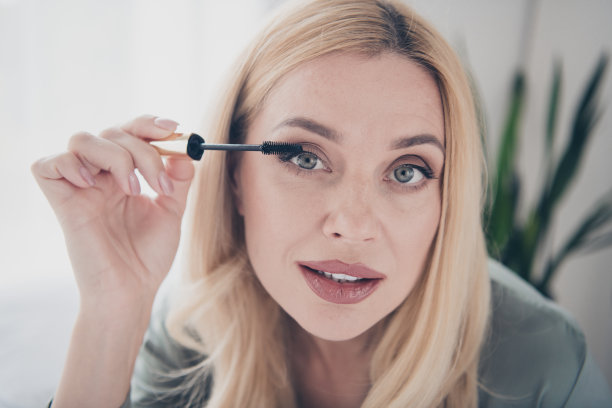 特写照片漂亮的年轻女子涂睫毛膏丝绸睡衣白色室内卧室公寓室内图片下载