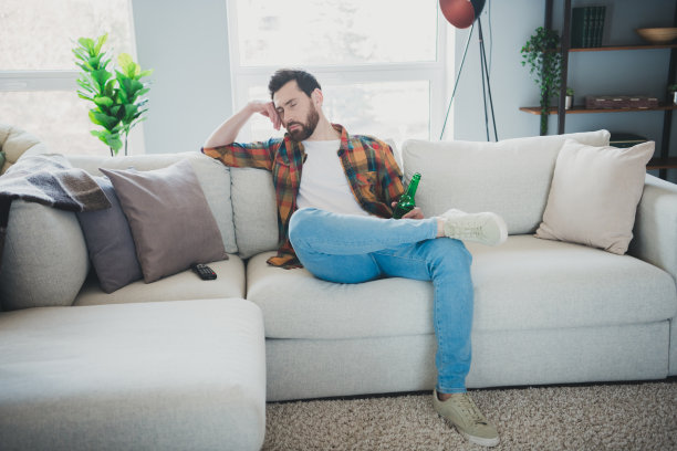 漂亮的年轻人的全尺寸照片坐在沙发上看电视睡觉累穿时尚的格子衬衫现代光舒适的室内平坦的室内图片下载