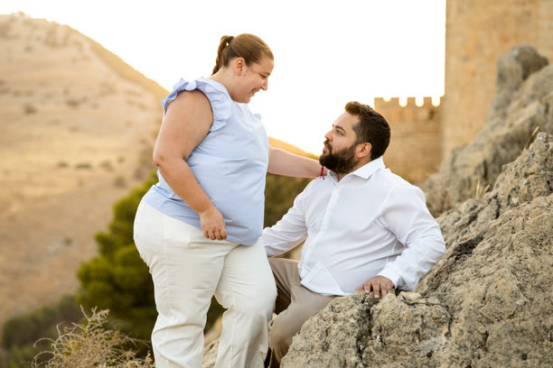 一对胖胖的夫妇在贾萨姆附近为婚礼拍摄了一些照片。这对夫妇互相看着对方，而男人则坐在一块石头上。填充人之间的爱情概念。图片下载