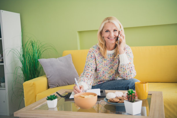 漂亮的老年妇女的照片讲电话写笔记本客厅公寓在室内图片下载