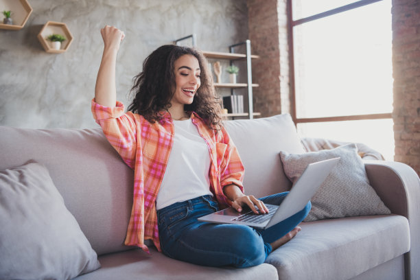 幸运的好心情的女人穿着橙色衬衫赢得游戏现代小工具在室内的房子公寓房间的照片图片下载