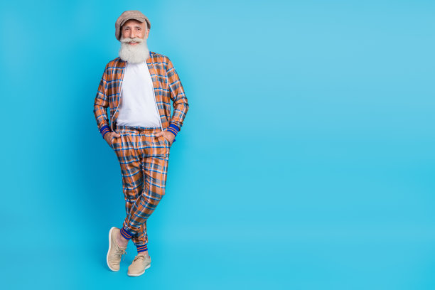 全身照片英俊的酷男人养老金领取者穿着格子服装手臂双手口袋空旷的空间孤立的蓝色背景图片下载