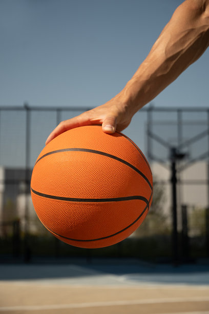 在蓝色的球场上，男子手里拿着橙色的篮球。运动背景。图片下载