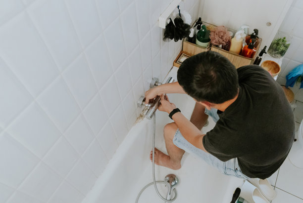 一个年轻人用手拧开墙上的水龙头。图片下载