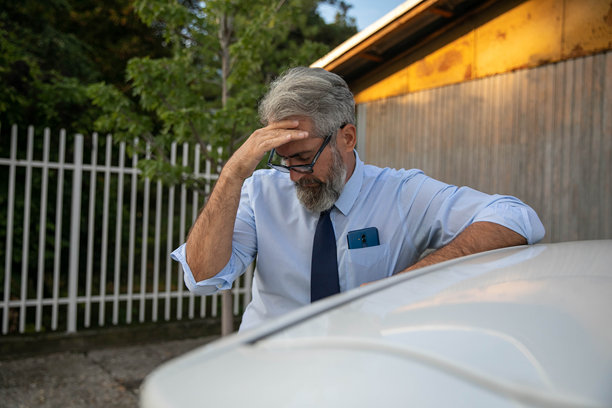 一位老人因为头痛在车旁抱头图片下载