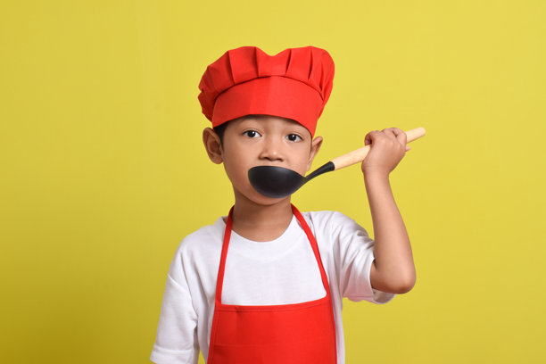 可爱的小厨师拿着勺子。亚洲男孩烹饪图片下载