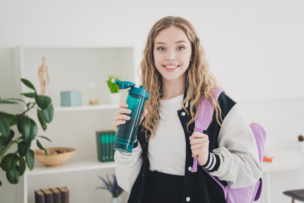照片的青少年金发甜美可爱的女士背包水瓶穿着时尚的制服寒冷的公寓卧室白光室内图片下载