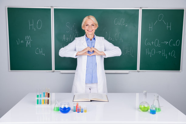 照片中，迷人开朗的高中女教师穿着白色大褂，孤立在绿板背景上图片下载