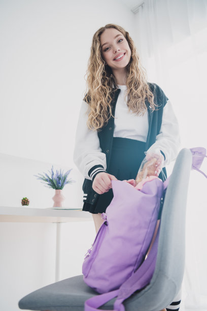 垂直照片的青少年金发甜美可爱的女士背包穿着时尚的制服寒冷的公寓卧室白光室内图片下载