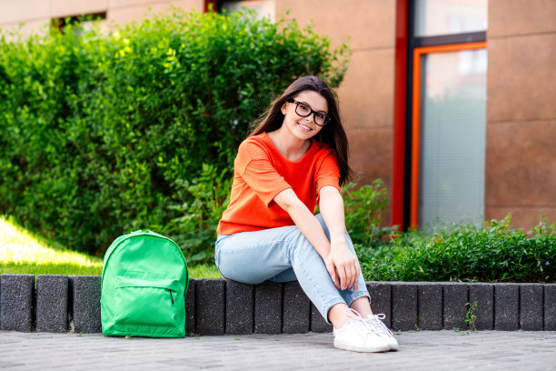 积极的青少年的全尺寸照片可爱的开朗的女人放松的大学生穿红色的衣服散步公园阳光明媚的春天天气外面图片下载
