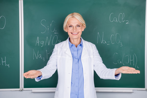 迷人的聪明的女教师的照片穿白色大褂邀请大学隔离在绿色的板背景图片下载