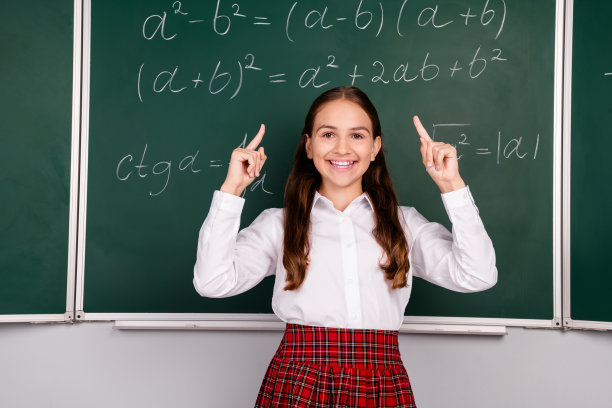 照片中迷人的十几岁的小学生女孩指着空旷的空间穿着时髦的校服教室黑板背景图片下载