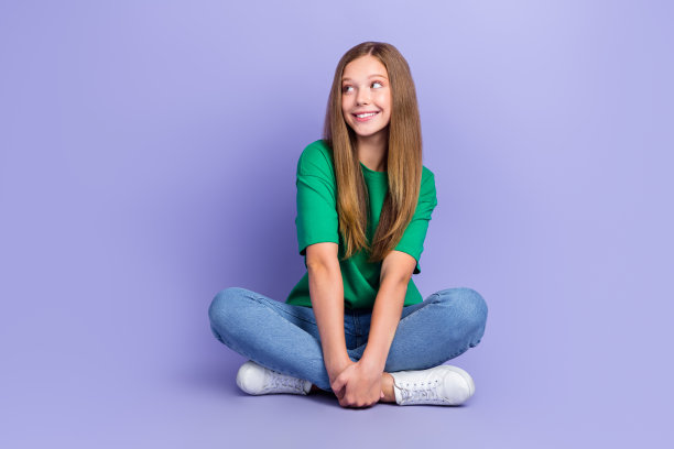 漂亮可爱的女学生的照片坐在地板上感兴趣的看空空间新奇酷提供孤立的紫色背景图片下载